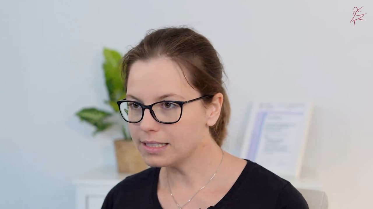 Eine Frau mit Brille spricht in einem hellen Raum in die Kamera