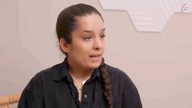 Eine Frau mit Zopf spricht im Interview vor einer hellen Wand